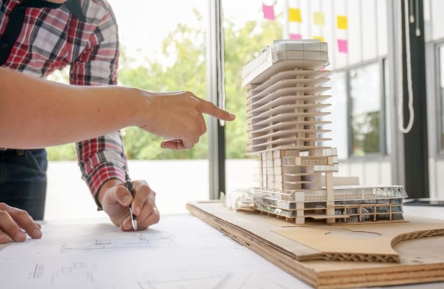 Architects discussing and examining a scale model of a residential building project.